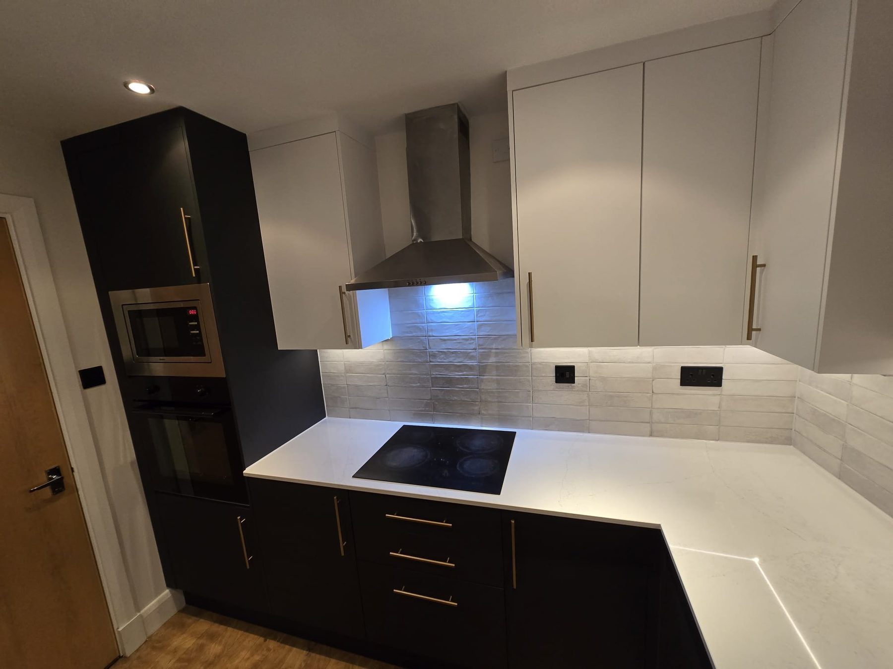 Finished kitchen with dark cabinets and white worktops